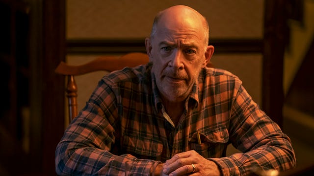 JK Simmons sitting at a dining table facing us.