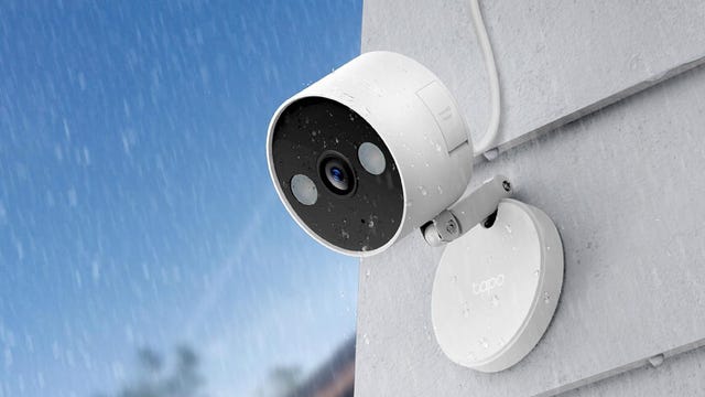 An illustration of the Tapo C120 camera mounted to white siding outside in the rain.