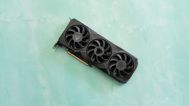 The triple fan side of the RX 7900 XT lying on a marbled green surface