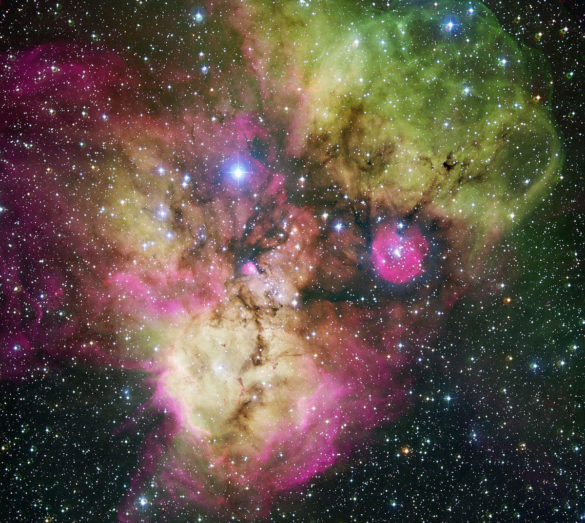 Angry-looking cosmic face seems to be glaring out from a nebula highlighted by ghostly wisps of green and pink.