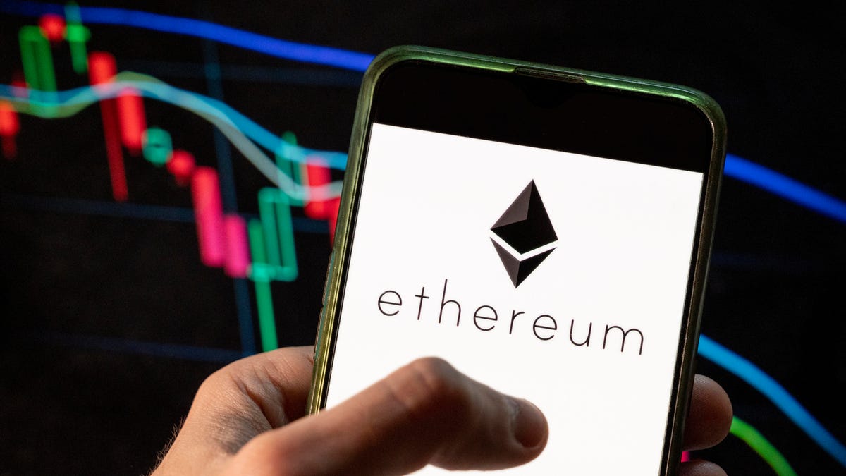 Ethereum's logo on a phone screen with a market graph in the background.