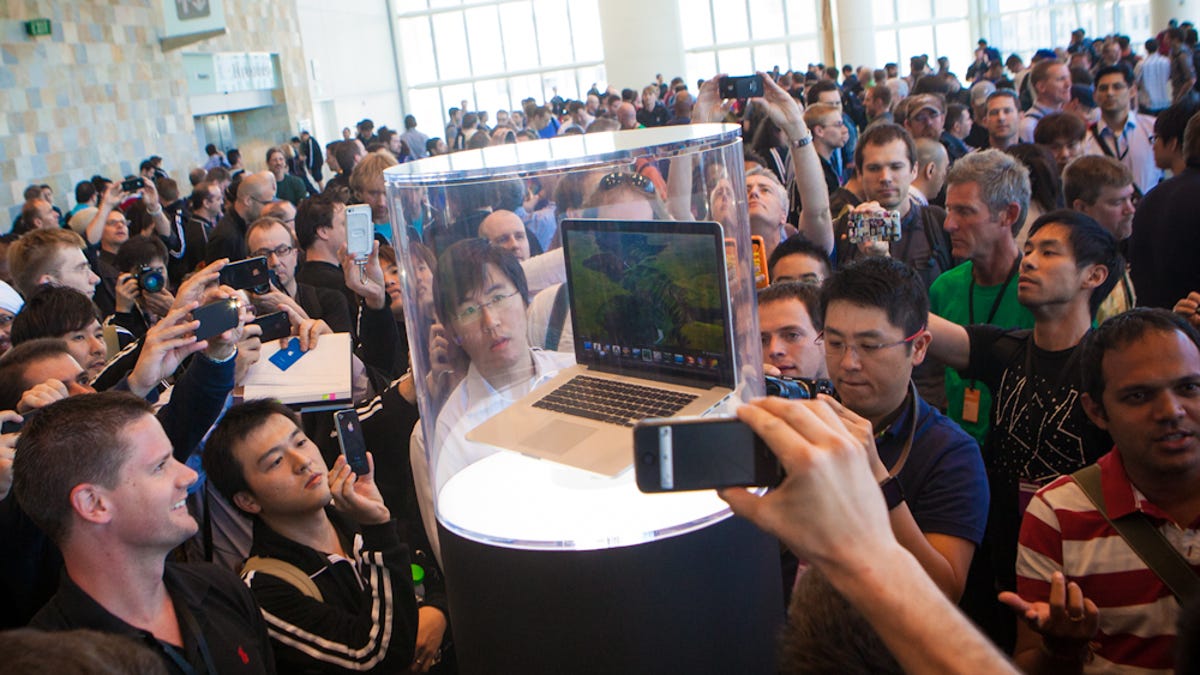 WWDC attendees crowding around enclosed versions of Apple&apos;s latest MacBook.