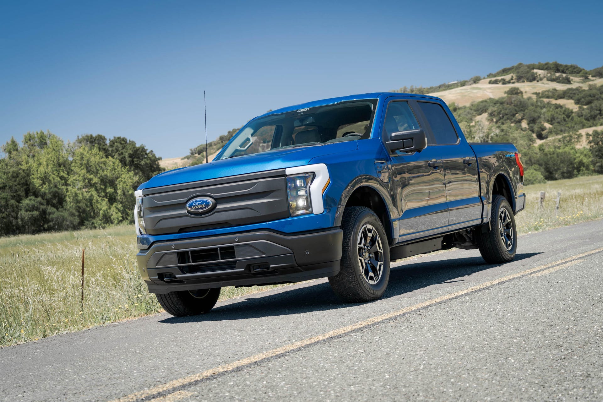 A blue Ford F-150 Lightning Pro pickup on the road