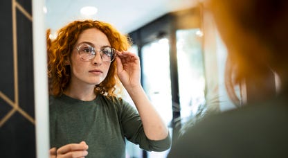 Woman trying on glasses in the mirror.