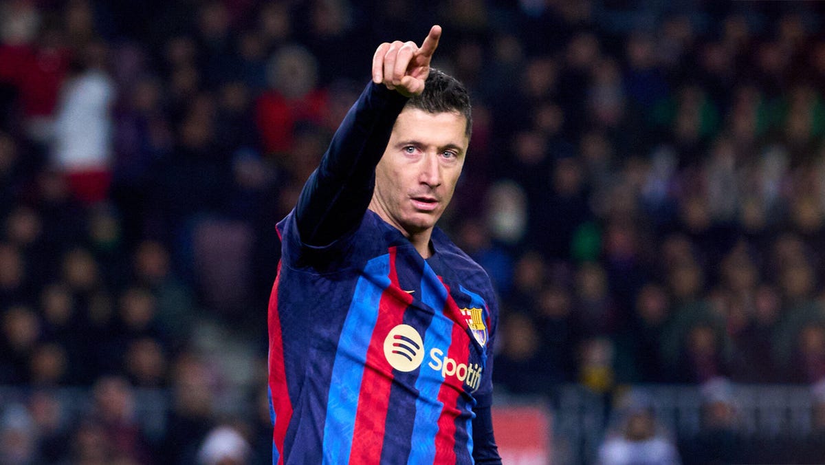 FC Barcelona striker Robert Lewandowski looks at the camera and points to the sky.