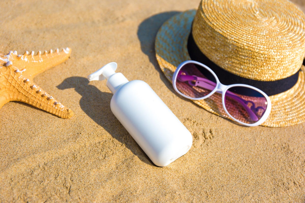 Bottle of sunscreen lotion on the sandy beach
