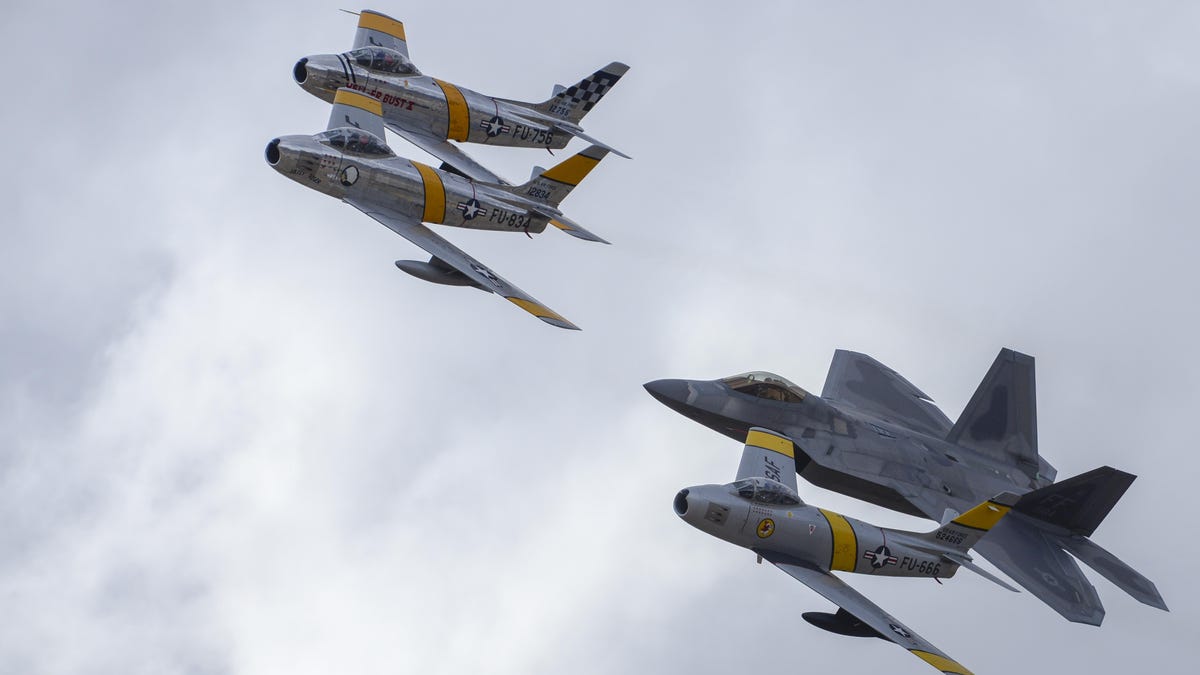 Three vintage F-86 Sabres fly in close formation with an F-22 Raptor.