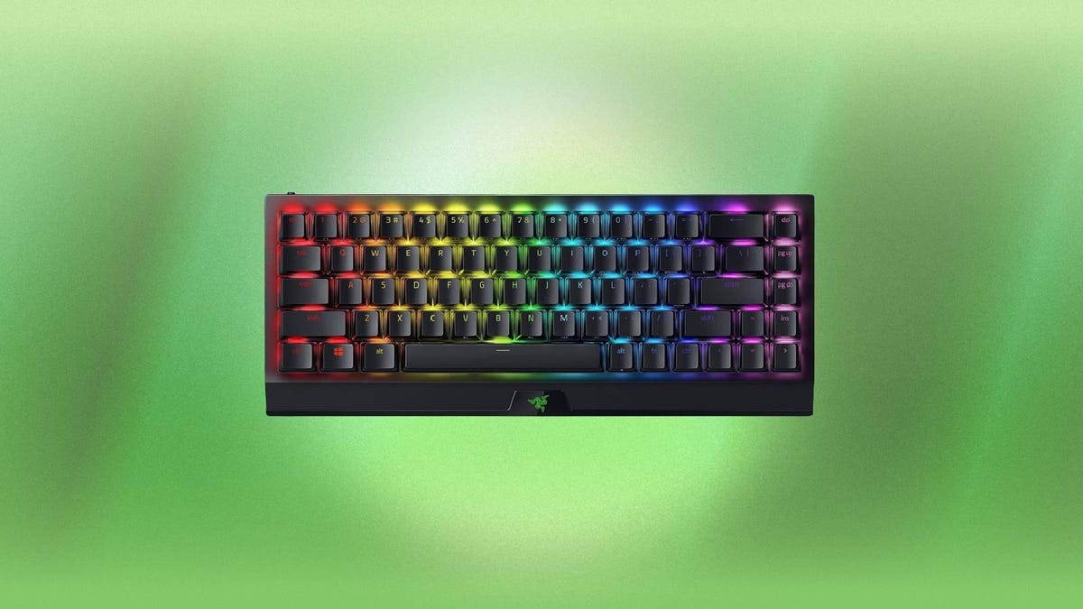 A black Razer keyboard with multicolor backlighting against a green background.