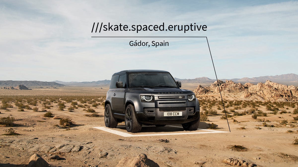a Land Rover Defender SUV parked on a spot in the Spanish desert labeled with What3words location technology