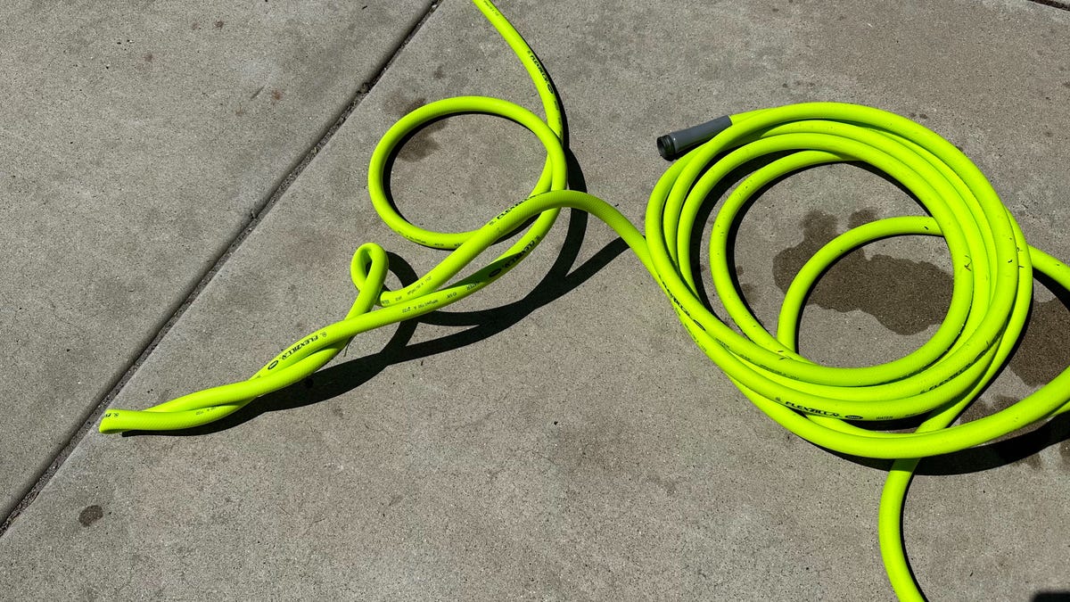 Flexzilla garden hose in bright green laying twisted on a driveway
