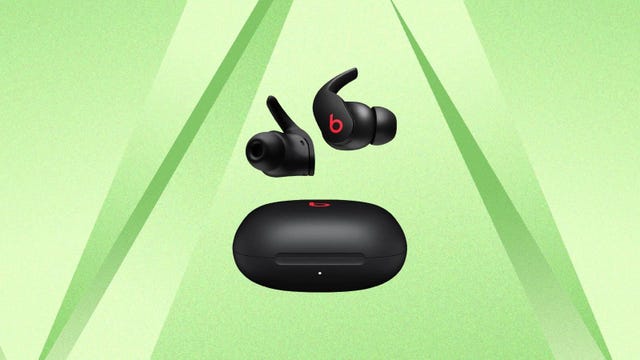 A black pair of Beats Fit Pro earbuds against a green background.