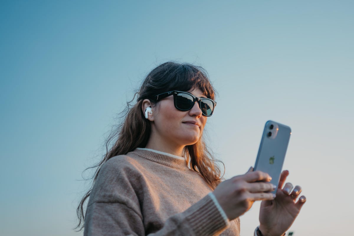 Woman wearing sunglasses using iPhone