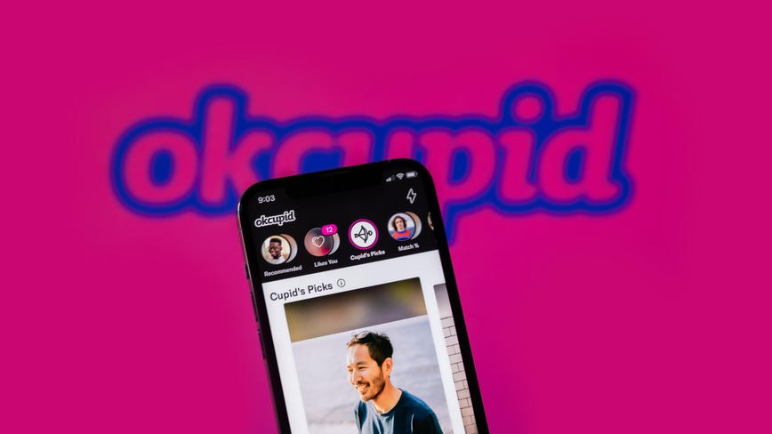 Dating app OK Cupid shown on an iPhone with the OK Cupid logo in the background