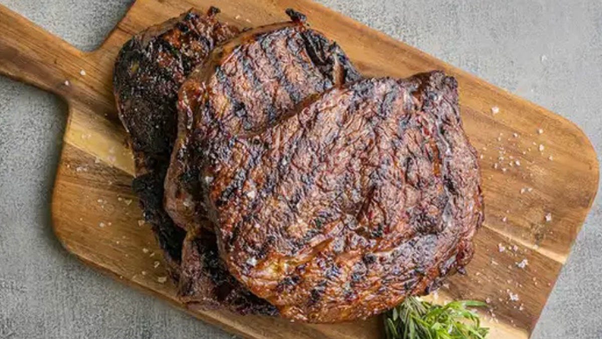 Three Steakhouse Ribeye steaks from Snake River Farms are displayed on a cutting board.