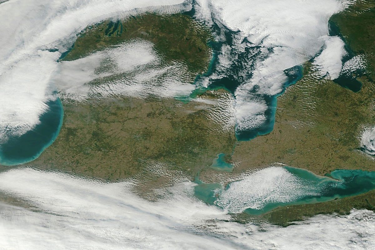 The Great Lakes region, with Detroit near the center, shows a portion of Lake Michigan through the clouds on the left, Lake Erie of the right, and Lake Huron at the top of the photo.