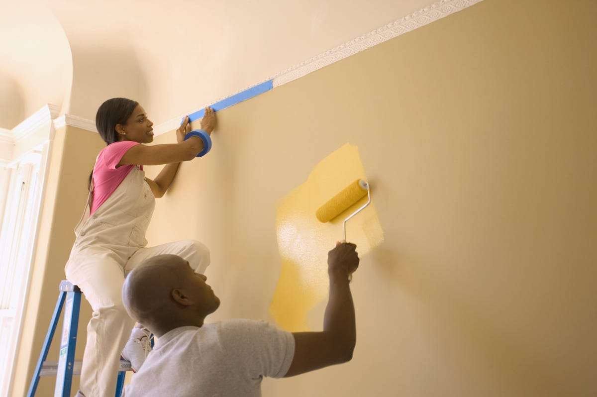 Two people painting their walls yellow