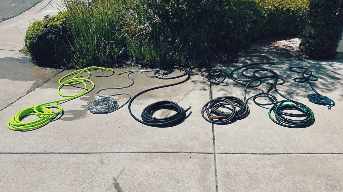 Showing 6 hoses coiled up laying on a driveway