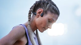 A woman using Shokz open-ear headphones during a workout