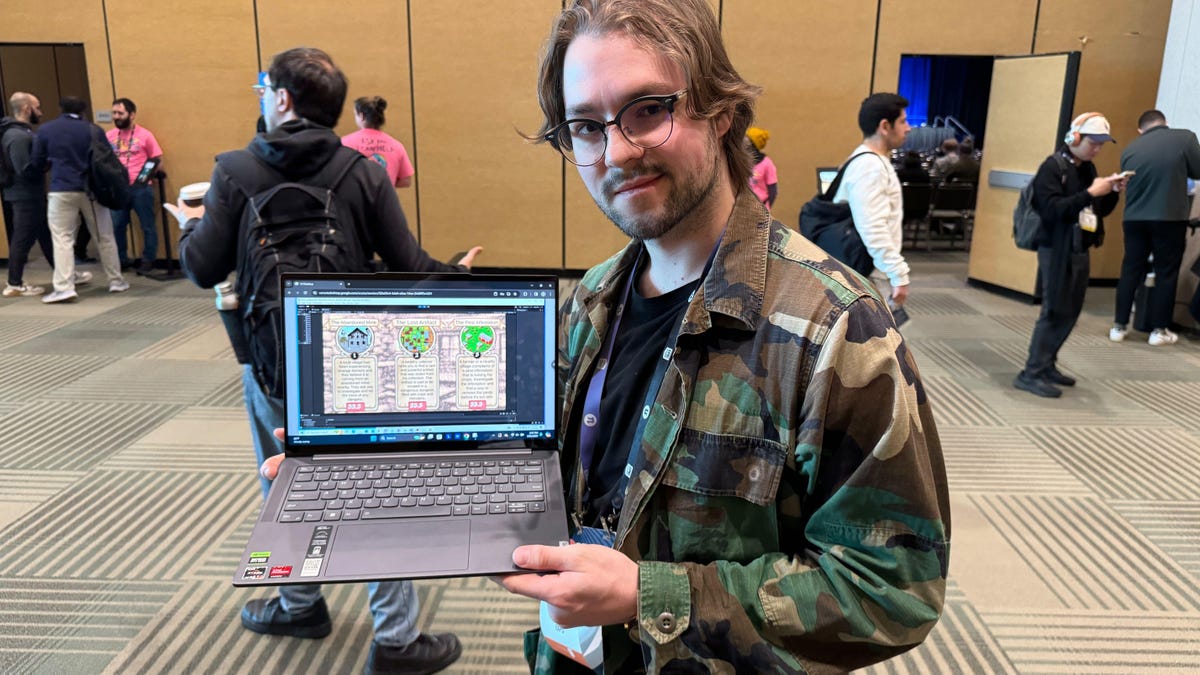A man stands with his laptop showing his generative AI game in progress shown on the laptop he's holding.