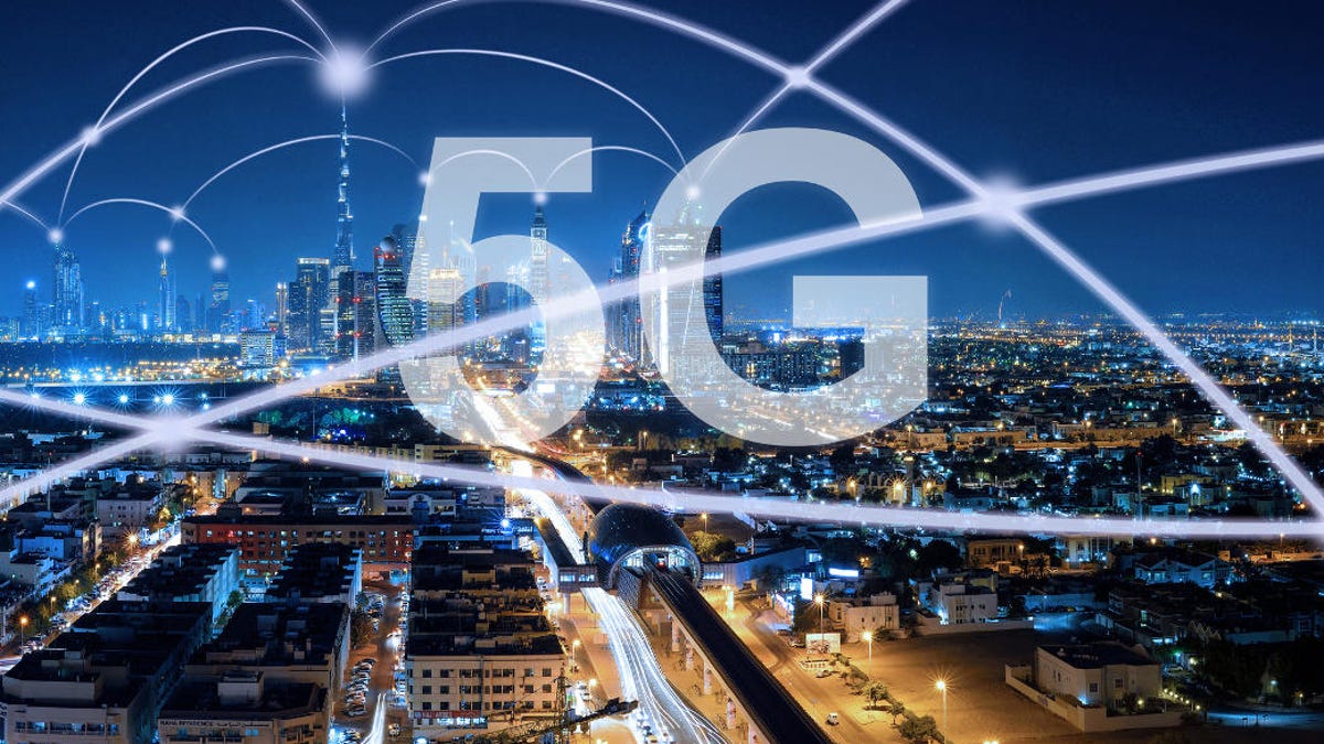 The term 5G floats atop a nighttime view of a city skyline. Curved lines of light represent speedy connections.