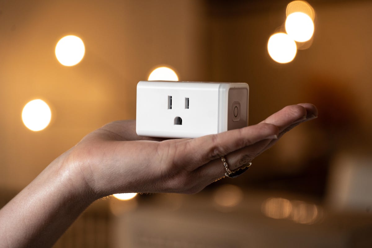 Someone holding a smart plug in their hand.