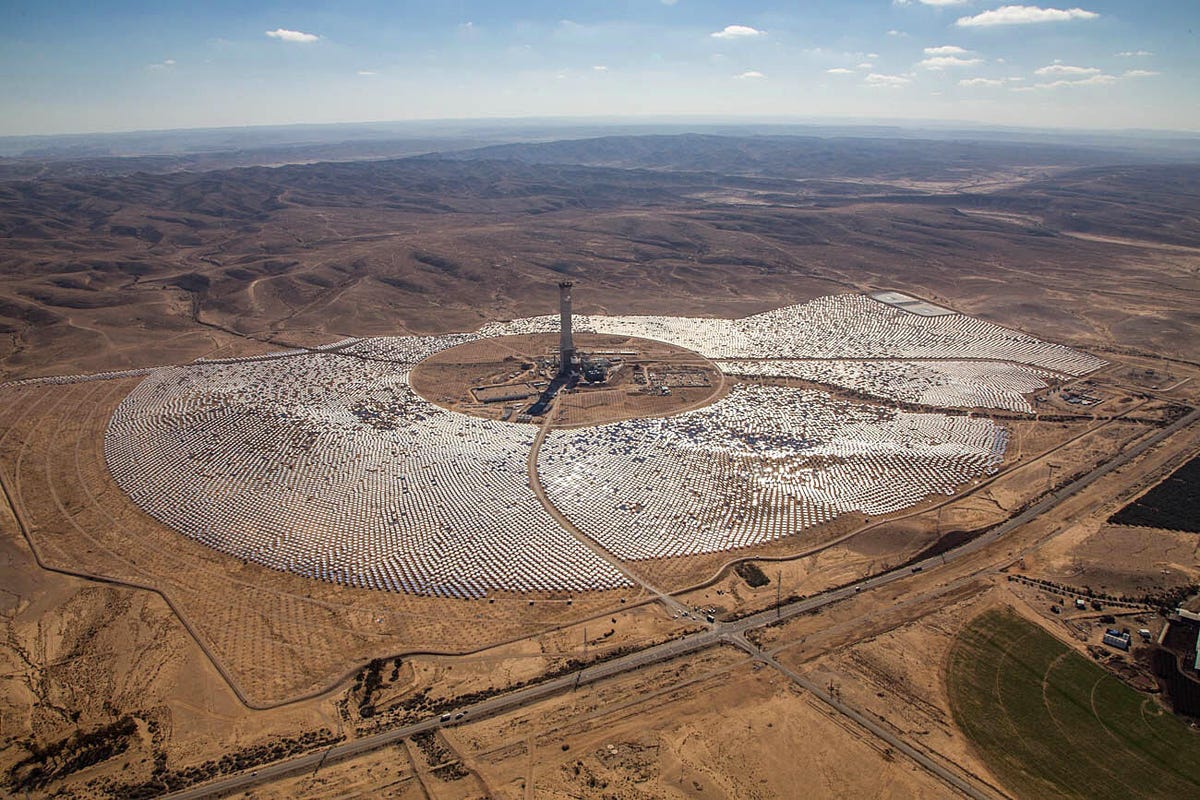 Thousands of mirrors on the desert surface point toward a large central tower of solar power station in Israel..