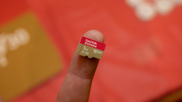 A 1TB microSD card on someone's fingertip.
