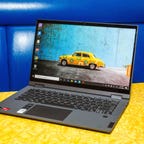 An open Lenovo Chromebook on a yellow tabletop against a blue background.