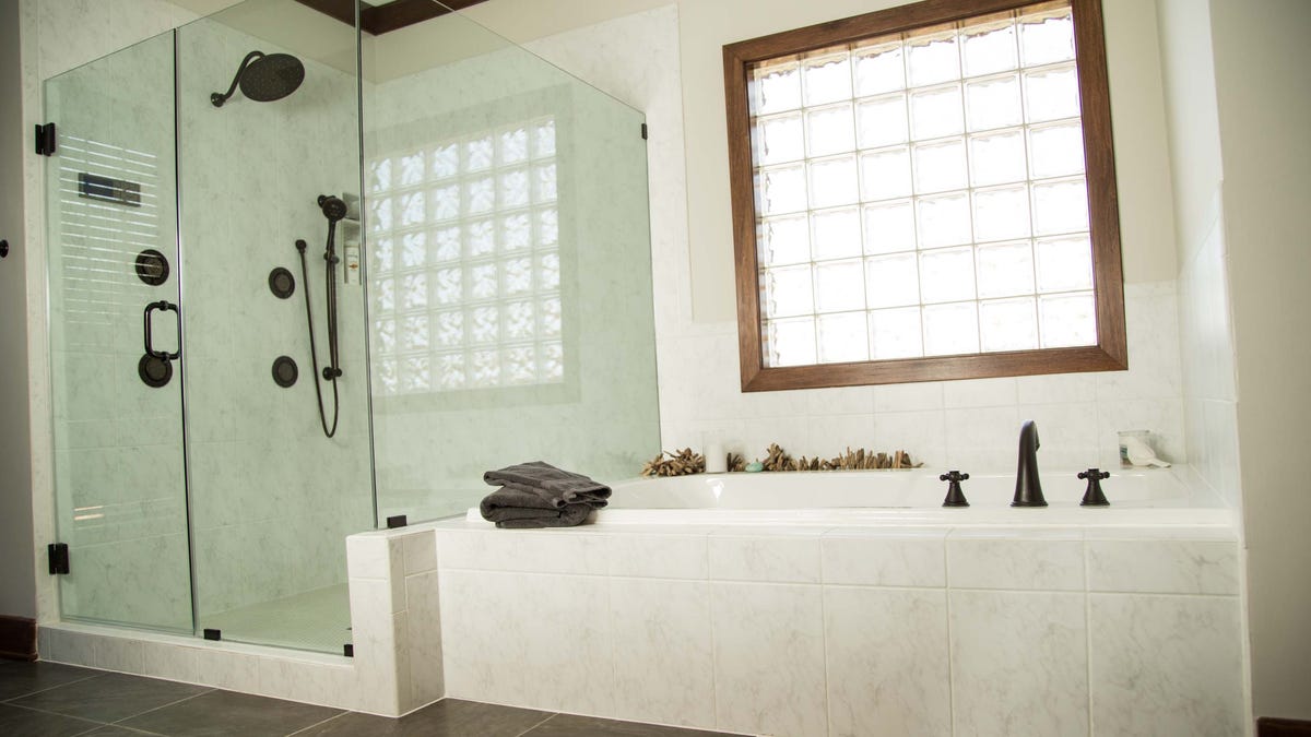 white tiled bath and double shower next to a large square window