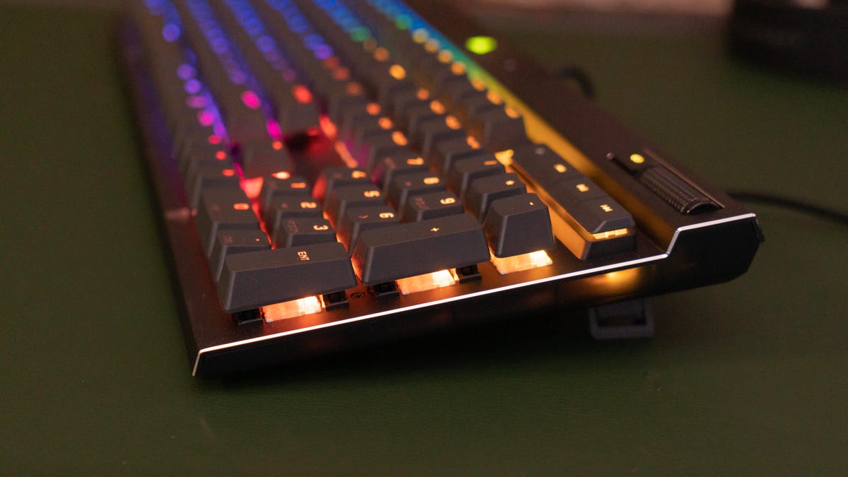 A side view of the keyboard on a green surface, with rainbow lighting of the switches