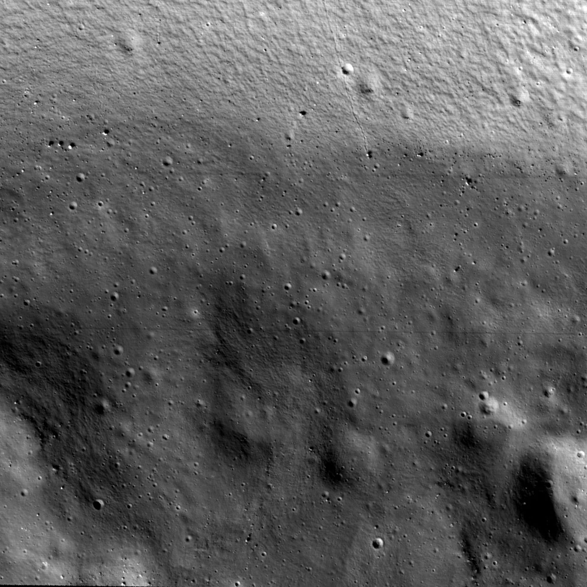 Square black and white view into Shackleton crater on the moon reveals boulders and pockmarks.
