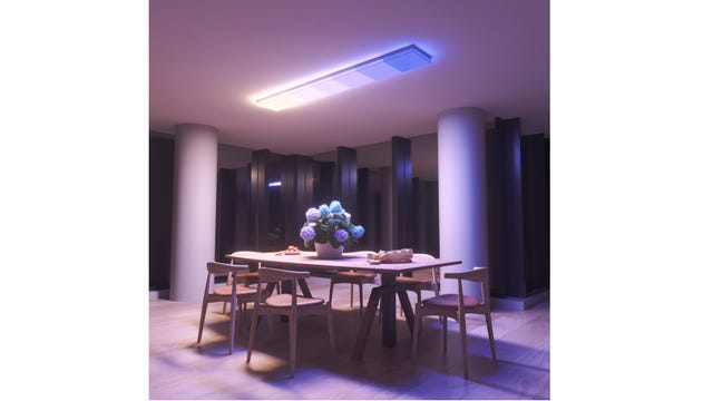 The Nanoleaf Skylight, a color-changing smart LED ceiling fixture, installed above a dining room table and casting a gradient of blue and white light across the room.