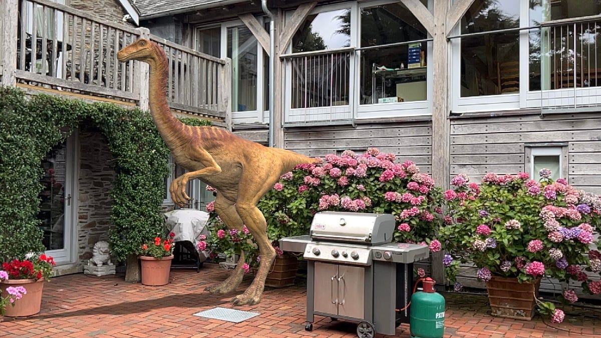 An AR dinosaur standing in a courtyard next to a grill.