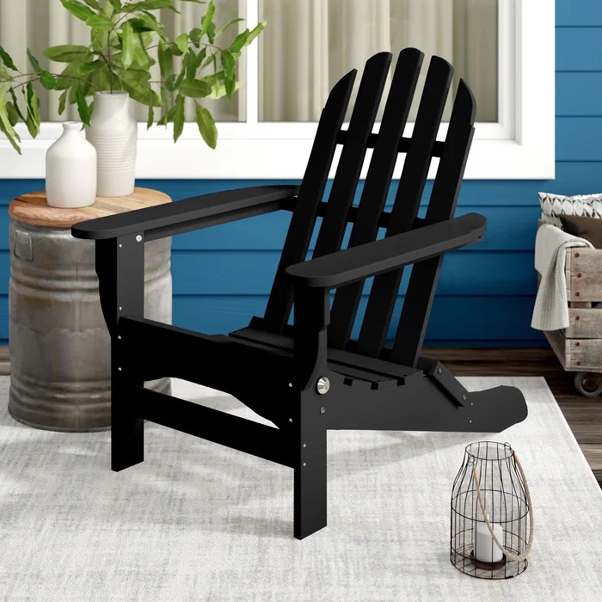 Black Adirondack chair on a porch with other outdoor decor