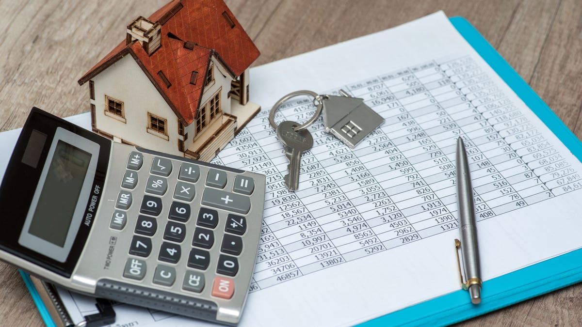 A photo illustration of a calculator, home loan paperwork and a mini house.