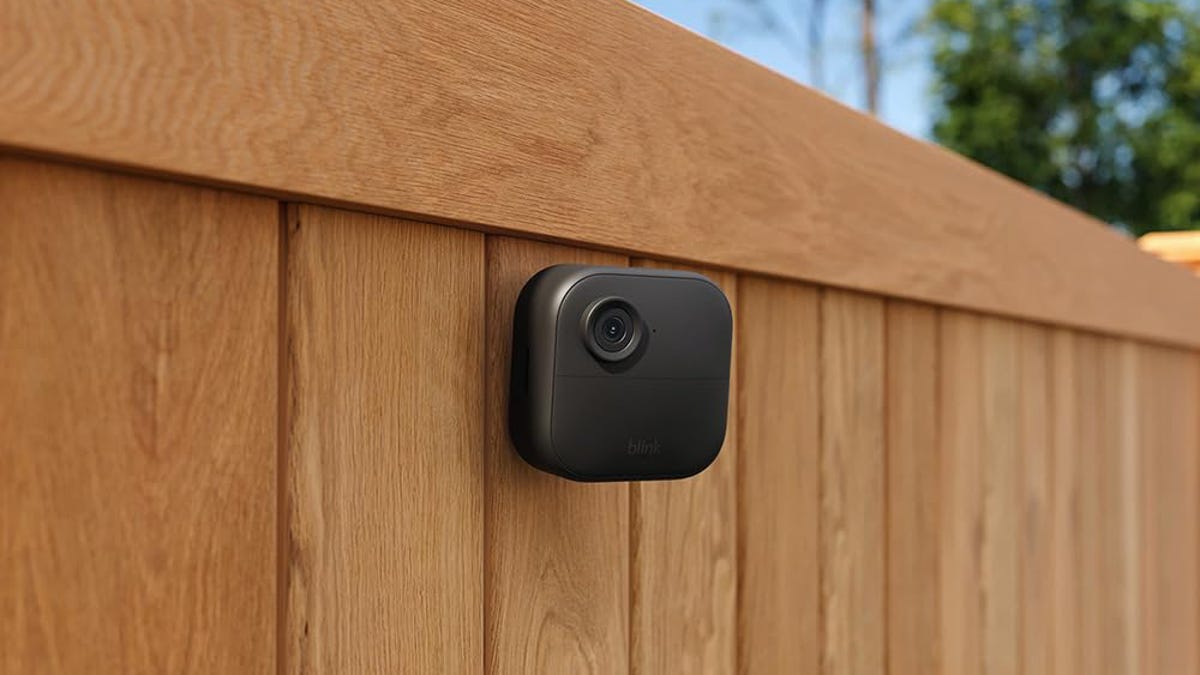 The wireless Blink Outdoor 4 security camera sits perched on a fence.