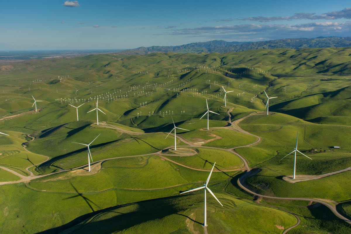 Aerial photo of wind turbines in green hills.