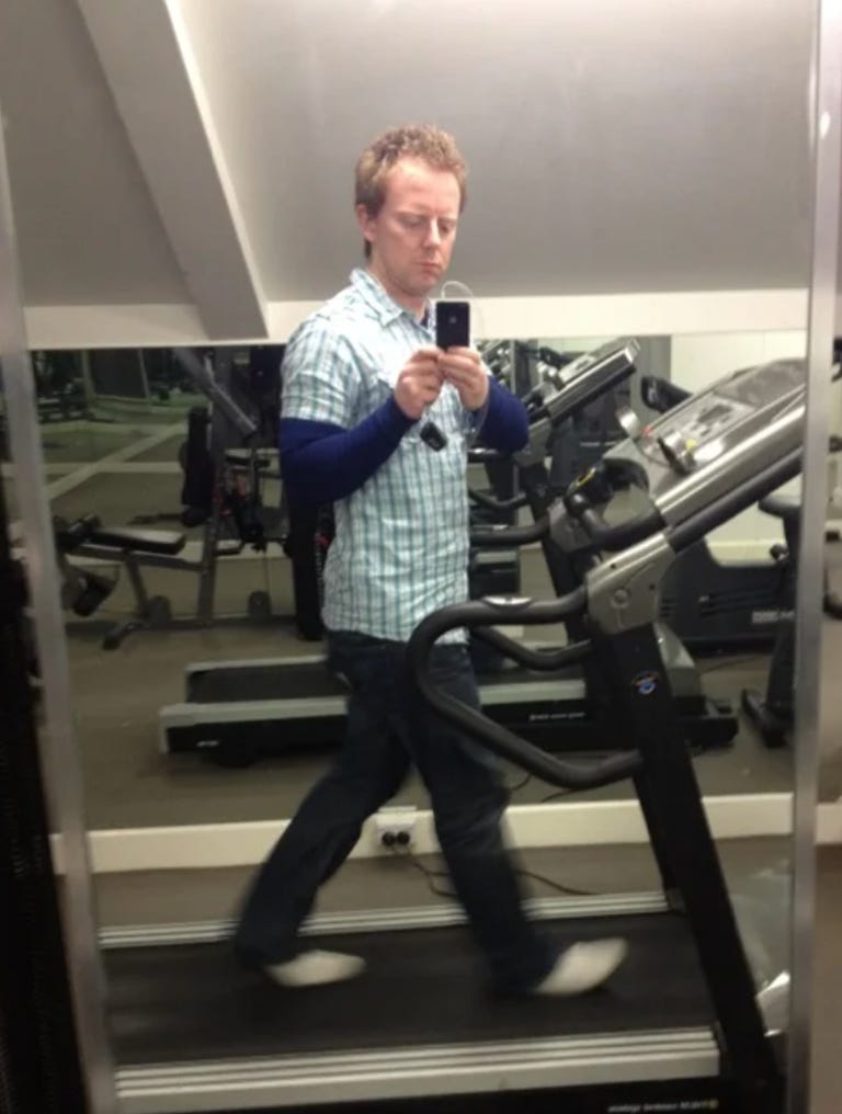 Man walking on a treadmill and looking at a smartphone