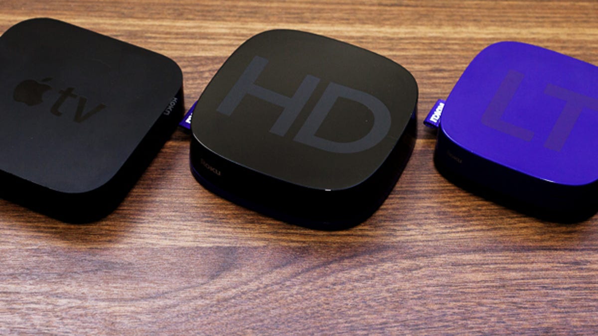The current Apple TV model next to two of Roku's boxes.