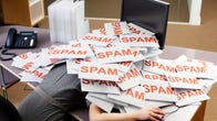 Person under a pile of papers which have the word "SPAM" printed on them in orange