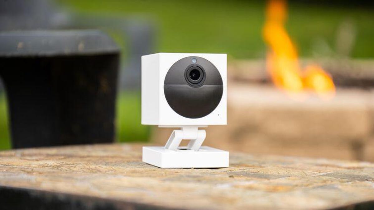 A white Wyze camera sitting on an outdoor table.
