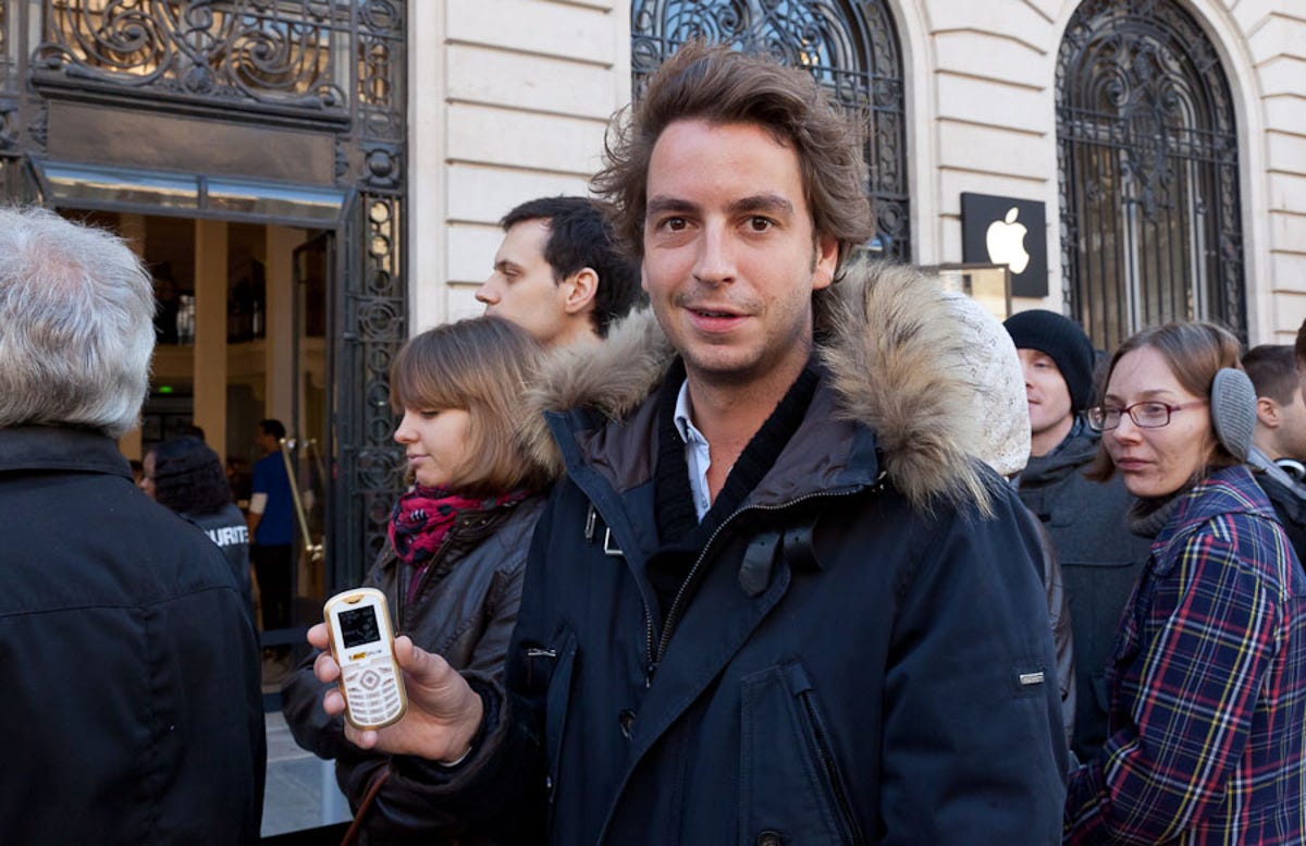 Paris resident Raphael Journé, about to buy his seventh iPhone, shows the "crappy" phone he's been suffering with for two weeks until Apple's latest smartphone went on sale.