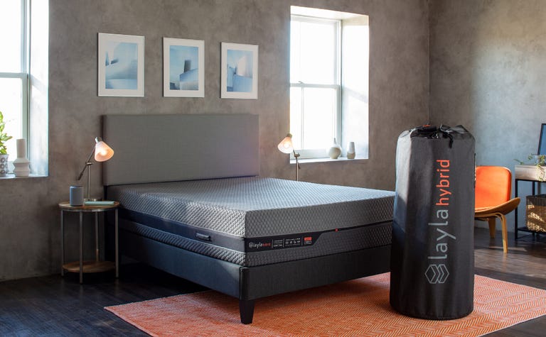 A queen size Layla mattress set up in a bedroom with a bed frame and orange rug