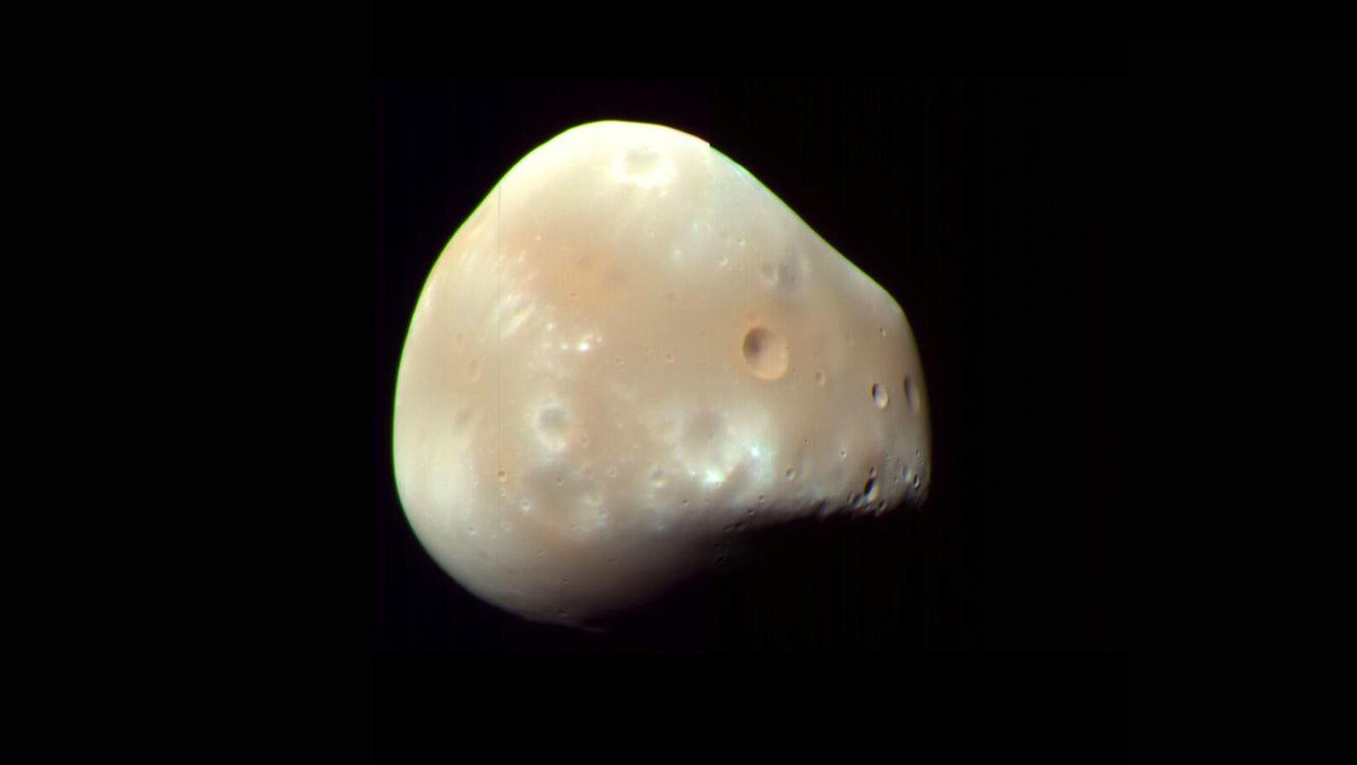 Lumpy, cratered little Mars moon Deimos against a black background.