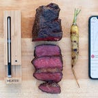 meater probe next to a medium rare steak and an iPhone