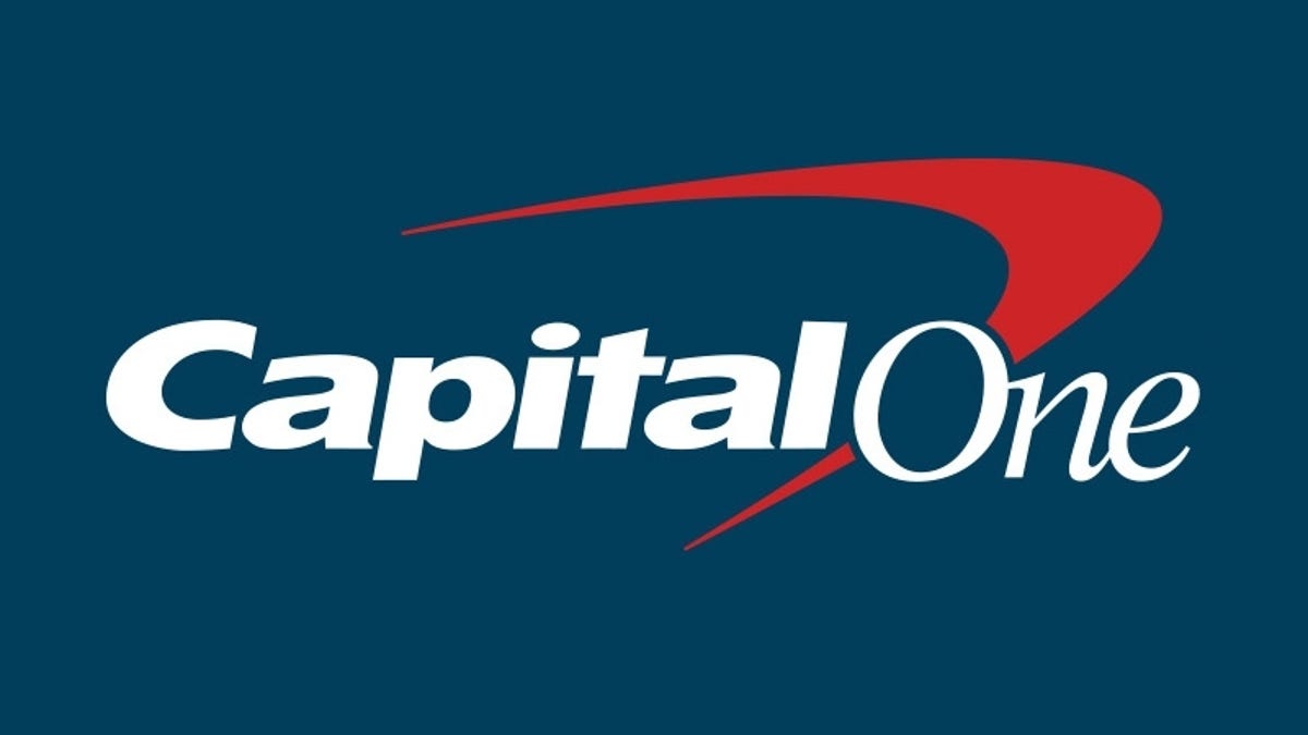 "Capital One" written in white italic font over a red boomerang on a blue background.