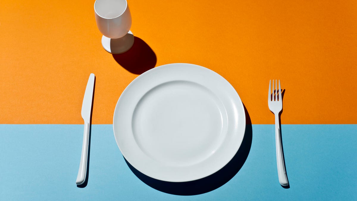 empty plate, fork and knife on a blue and orange bold background