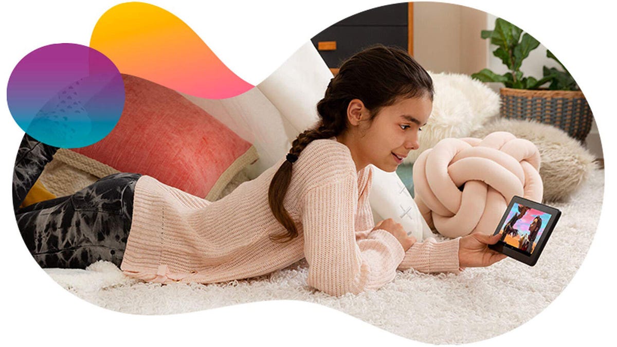 A girl lies on her stomach and watches Amazon Kids Plus content on a tablet.