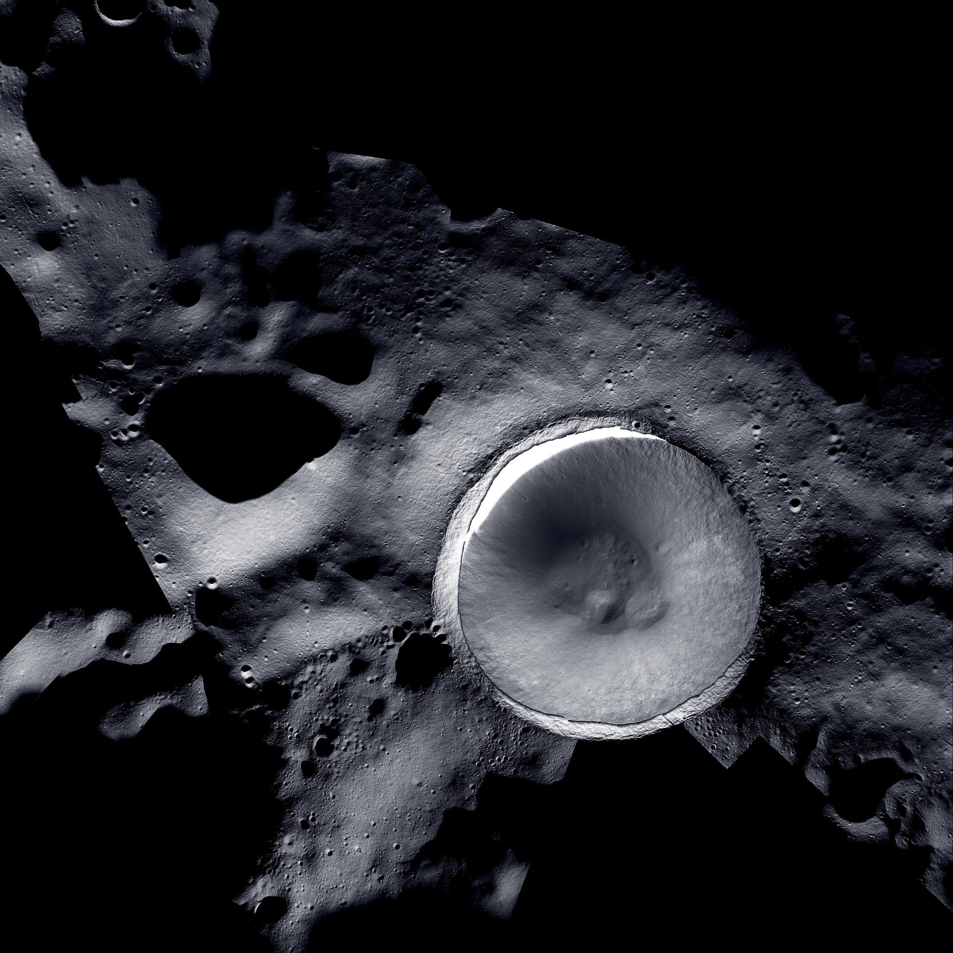 Stark black and white view of lunar surface with Shackleton Crater as a large round, brighter divot against a cratered dark landscape.