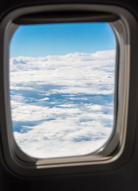 View of clouds through the window of a passenger jet.